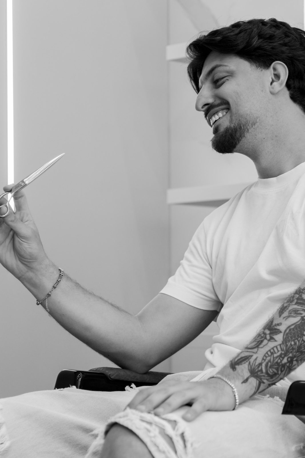 Simone Matassa sorridente con le forbici in mano nel suo studio